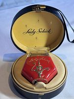 The Lady Schick electric razor displayed inside the open vintage black leather carrying case with satin yellow lining and logo.