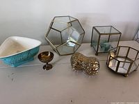 Photo showing all six decorative items including ceramic bowl, brass egg cup, silver peanut-shaped piece, and three geometric glass terrariums