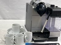 Machine with four espresso cups on saucers visible