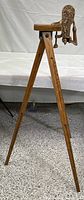 Full view of the wood tripod floor stand with brass wine bottle opener mounted on top, showing the overall height and tripod legs.