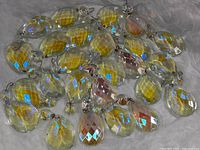 Close-up showing iridescent yellow-gold faceted crystal chandelier prisms with teardrop and oval shapes and wire hooks.