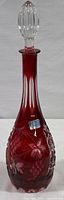 Full view of ruby red cut-to-clear lead crystal decanter with floral and geometric designs, original sticker visible on body.