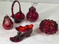 Lot overview photo showing all five ruby red glass items: slipper shoe, covered dish, two pear figures, and flower basket with leaf