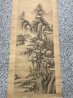 Full view of the vintage Japanese scroll painting depicting a mountainous landscape with waterfall and trees, showing the entire scroll and border.