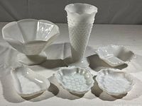 All six milk glass items grouped together: hobnail vase, footed fruit bowl, two strawberry/cherry motif dishes, diamond pattern candy dish, and pear-shaped candy dish.