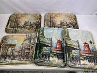 Five fiberglass serving trays arranged on a table, showing three distinct Paris landmark scenes with two trays each for Moulin Rouge and Notre Dame, and one tray with Arc de Triomphe.