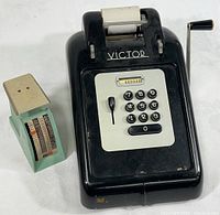 Vintage Victor adding machine and small Hanson postal scale side by side on a flat surface