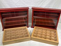Two finished wooden wall shelves with hinged glass doors in reddish stain with two unfinished wooden compartment boxes with plexiglass sliding covers, viewed from above to show compartments and fronts.