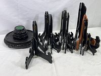 All wood and one plastic plate stands and pot bases arranged on a white surface, showing various sizes and styles.