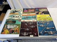Photo showing multiple classical music vinyl records on a table. Covers include illustrations of baroque musicians and instruments. Records are 12 inch size with visible signs of wear.