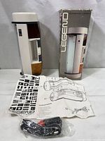 Legend Systematic Lantern displayed alongside original box, instruction manual, and wiring cable in plastic bag. Lantern made of white plastic with red and amber color sections, tall and slender shape.