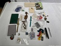 Complete view of various jewelry and accessories laid out on a white surface including watches, beads, buttons, small bags, and pins.