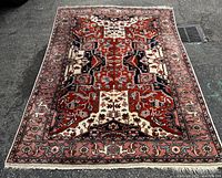 Full view of the vintage wool area rug laid out on a paved surface, showing the entire geometric pattern and borders with multicolor tones.