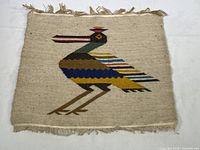 Tapestry showing entire bird motif with fringed edges on plain background