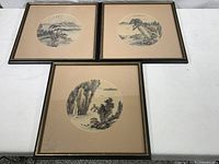 Three framed Asian silk landscape prints laid on table showing full lot contents