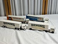 Four vintage moving company promotional diecast trucks on white fabric background showing Bekins, Allied Van Lines, and North American Van Lines logos and designs.