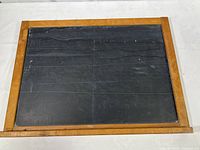 Full view of vintage rectangular chalkboard with natural wood frame and black slate surface showing wear.