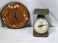 Photo showing vintage hand-painted wall clock with florals beside Universal kitchen scale.