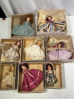Eight vintage Nancy Anne Storybook Dolls displayed in original boxes, featuring dresses in various colors and styles, some with hair ribbons or hats.