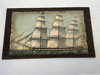 Front view of the vintage nautical painting on wood showing the sailing ship with three masts and full sails in a rustic dark wood frame.