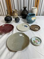 Nine vintage ceramic, porcelain, and stoneware containers and plates arranged on a table