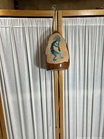 Front view of the wooden wind chime showing the Kokopelli figure and metal hanging elements.