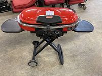 Front view of assembled grill with lid closed and slide-out side shelves extended