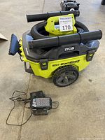 Ryobi cordless ONE+ wet/dry vacuum with hose attachments and charger with battery on concrete floor.