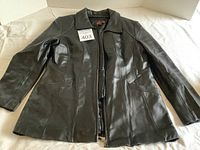 Front view of the black leather jacket showing the overall condition and design, with zipper closed and collar visible.