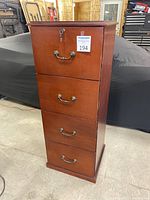 Front view of the wood filing cabinet showing four drawers with metal handles and a lock on the top drawer.