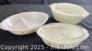 Three glass casserole dishes including two Glasbake with green daisy flower pattern and one plain white Anchor Hocking dish with lid