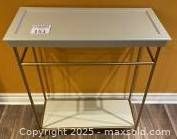 Front view of hallway table showing beige top with recessed border and brass frame