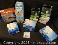 Photo showing nine boxes of assorted new light bulbs including NOMA, EcoSmart, and Feit Electric brands, various wattages.