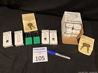 Photo of green Master Lock lock-out padlocks with packaging boxes, two keys per set, and seller auction tag and pen present.
