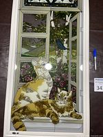 Full view of stained glass panel with two cats on windowsill and floral garden background.