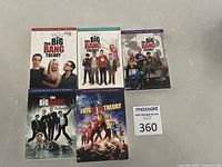 Five DVD cases of The Big Bang Theory seasons 1-5 displayed on a flat surface showing front covers.