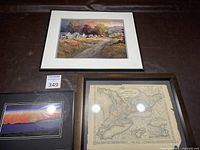 Three framed pieces of wall art including landscape painting, abstract art, and vintage map, laid out on surface
