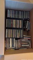 Box full of various CD jewel cases stacked flat and upright showing size and quantity.
