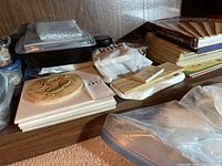Photo showing stacks of ceramic tiles, crafting molds, books and magazines, along with plastic containers holding small crafting pieces