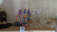 Photo of glass jugs, bowls, colorful ceramic candle holder, salt and pepper shakers on shelf.