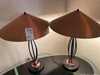 Pair of retro style table lamps with conical brushed copper metal shades and black oval bases with black rod and copper coil design