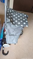 Side view of grey polka dot fabric shopping cart bag attached to metal frame with wheels and handle.
