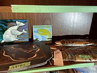 Four ceramic fish plaques with various colors and sizes including the largest at 20 inches, placed on a shelf.