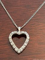 Close-up of open heart-shaped pendant with round diamonds on wood background