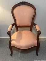 Front view of the Victorian armchair showing carved wooden frame and pink fabric upholstery