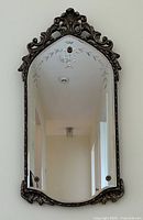 Front view of full mirror showing shape, carved silver leaf frame, and etched glass decoration.