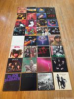 32 album jackets laid out in 4×8 grid on hardwood floor