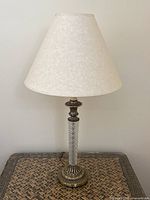 Single lamp showing crystal cut glass and brass toned base with off-white fabric shade