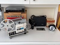 Complete lot showing Copal CP77 8mm projector with original box, Glenwood movie light with original box, black camera case, and Rollei SL82 camera.