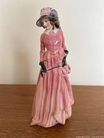 Full view of Royal Doulton Maureen porcelain figurine depicting a woman in pink dress with black gloves and feathered hat, holding a riding crop.